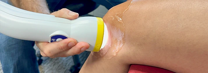 Shockwave Treatment Wand Being Used On Someone's Knee